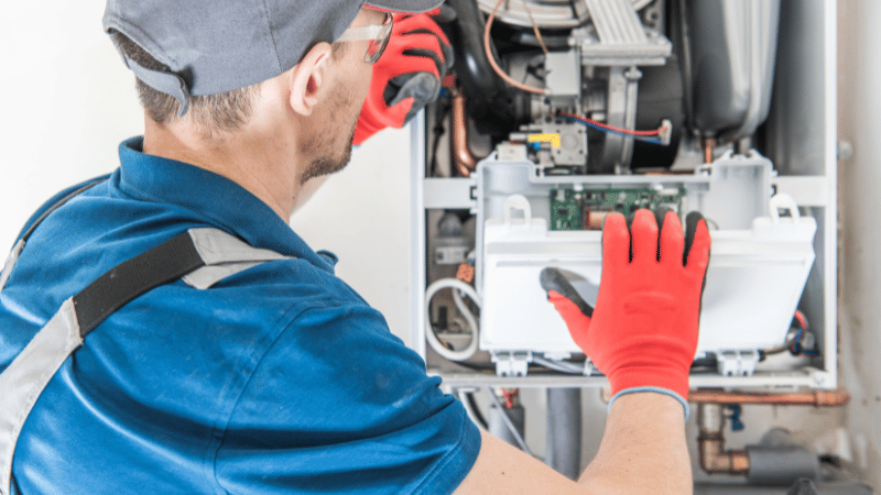 HVAC technician servicing a central gas furnace during a routine heating system inspection.